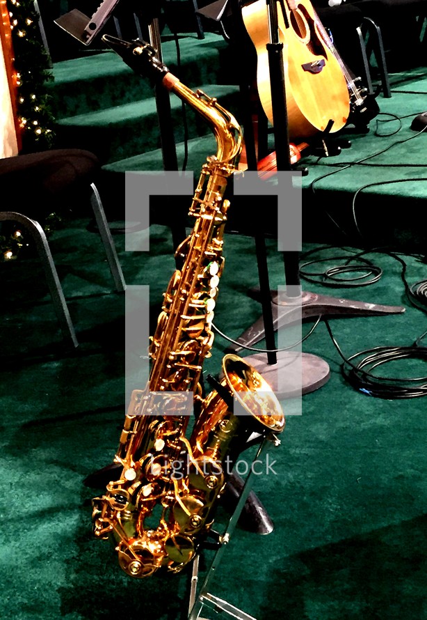 saxaphone on a church stage along with acoustic guitars and other musical instruments set up on a sound stage in preparation for a Sunday morning hour of praise and worship music. 