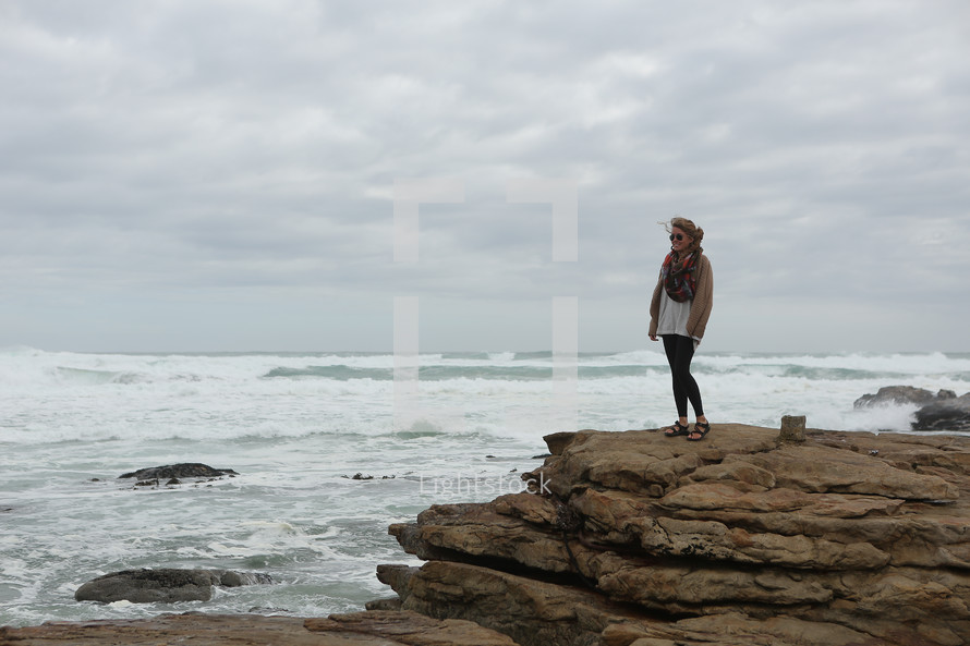 Woman standing on large rocks on ocean