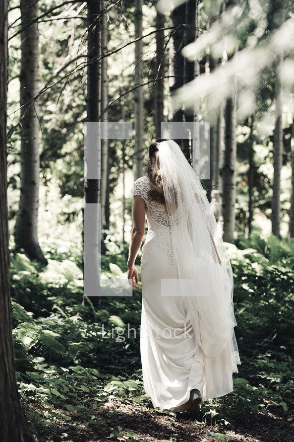 bride walking through a forest 