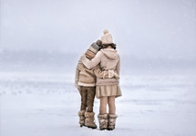 siblings hugging in the snow 