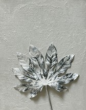 painted leaf lying on white textural canvas 