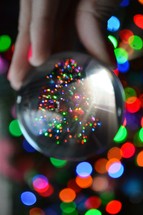 bokeh Christmas lights and Christmas tree reflection in a glass orb