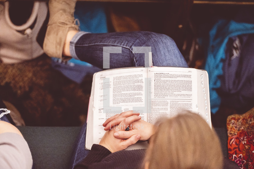 Bible in the lap of a woman sitting in church 