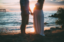 expecting couple holding hands on a beach 