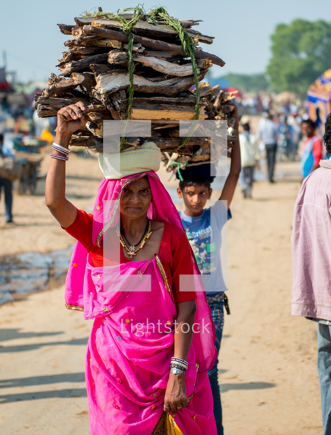 woman and boy carrying items on their heads in India 