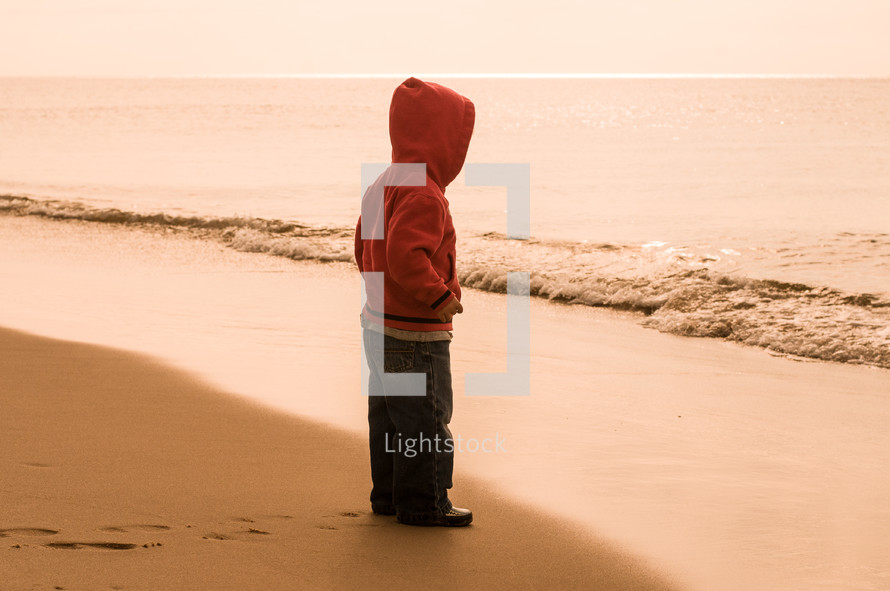 toddler boy standing on a shore 
