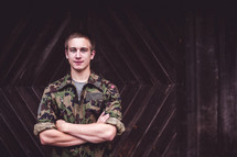 a man in camouflage with arms crossed 