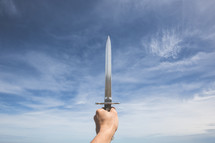 A hand holding a long knife to the sky.