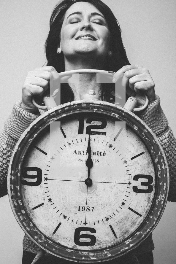 woman holding a clock at midnight 