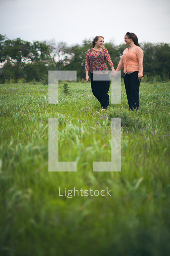 mother and daughter holding hands in a field 