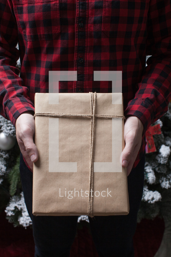 man in a plaid shirt holding a wrapped gift 