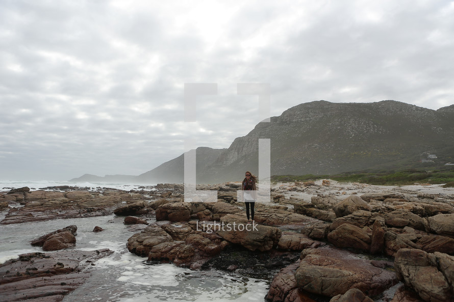 Woman standing on rocks on a coastal shore
