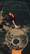 Young men playing basketball on an outdoor court on a sunny day