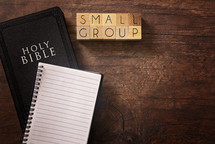 Bible and notebook on a wood background - small group 