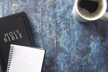 Bible, notebook, and coffee mug on a blue grunge background 