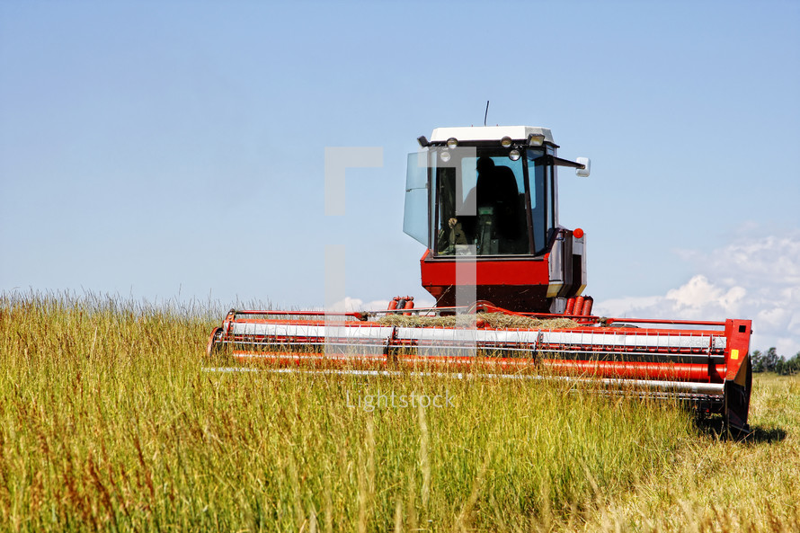 Harvesting a grass field for agricultural use in feeding livestock.