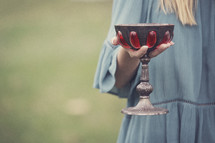 a woman holding a wine chalice 