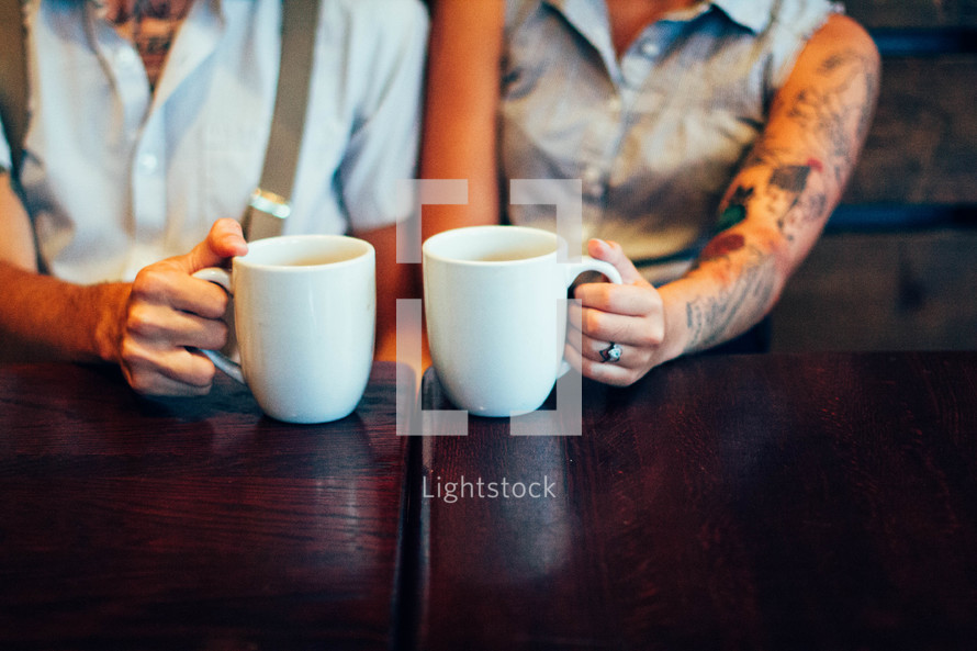 couple holding coffee mugs 