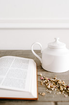 opened Bible on a table and tea pot