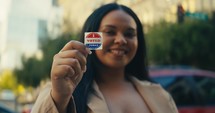 Young woman smiling with an ‘I Voted’ stickers and pin 