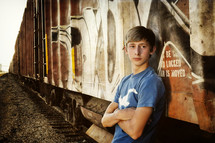 A teenage boy leans up against a train
