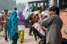 man getting a shave on the streets in Delhi, India 