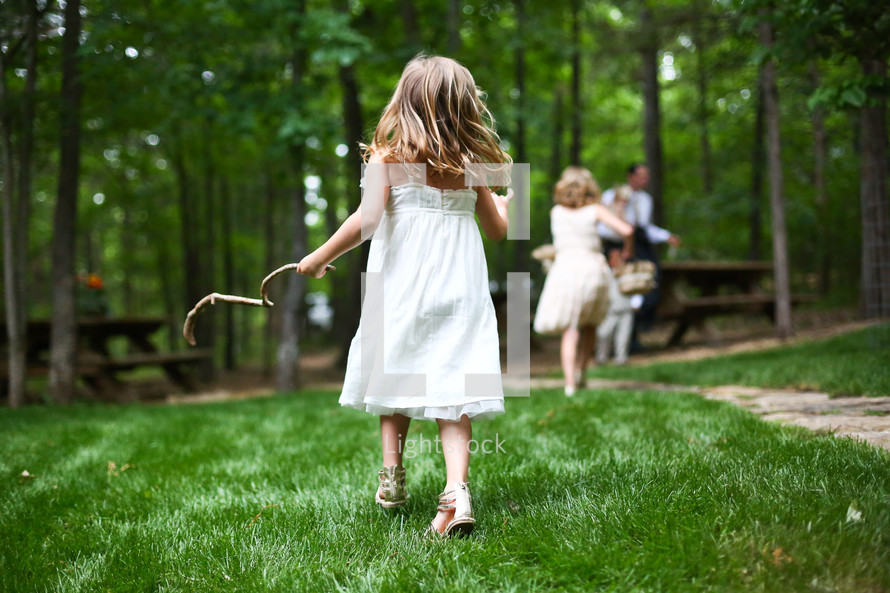 little girl running holding a stick in the park