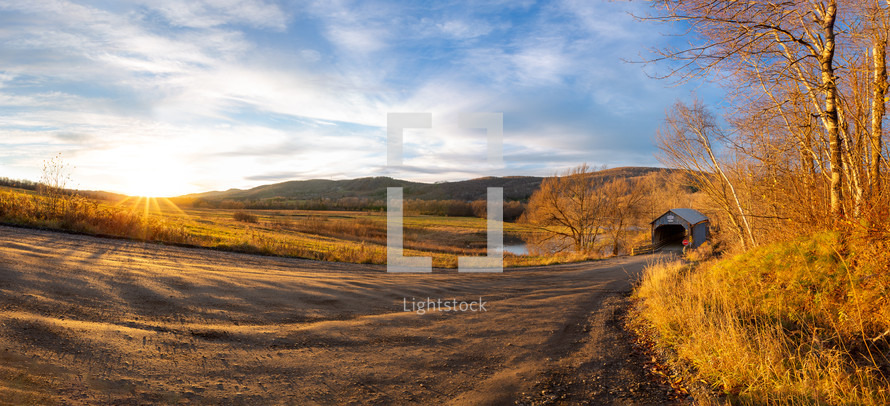 Path leading to covered footbridge during autumn panorama