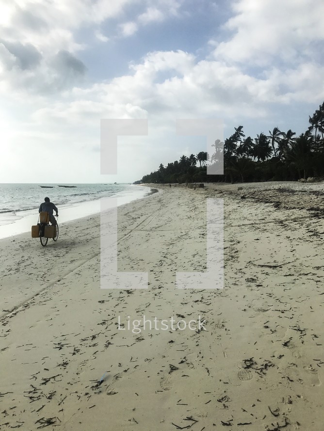 man riding a bicycle on a beach in Zanzibar, Tanzania