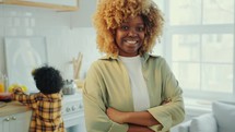 Portrait of Positive Black Woman with Arms Crossed in Well-Lit Kitchen
