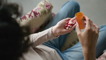 Woman Pouring Overdose of Pills from Prescription Bottle into Hand
