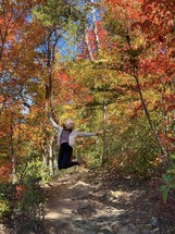 Woman in winter hat jumping in autumn trees