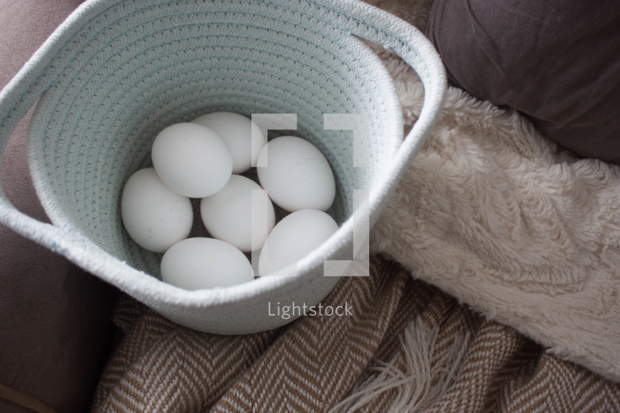 fresh eggs in a basket on a couch 