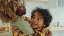 Loving African American Mother Holding Little Son as Bonding at Home
