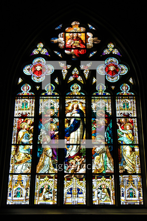 A huge stained glass window with multiple panels tells the story of Jesus Christ in an old historic church that is almost 200 years old in the southeastern United States. 