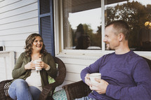 husband and wife having coffee on a front porch 