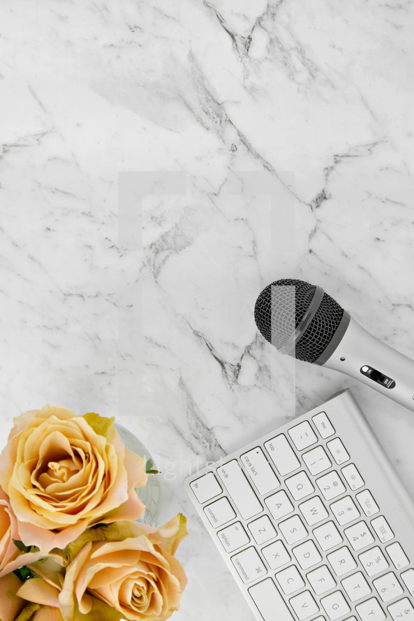 microphone, computer keyboard, and yellow roses on a marbled background 