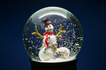 a snowman in a snow globe against a blue background 