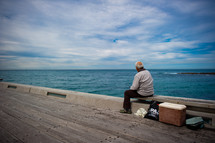 man sitting on a bench on a pier