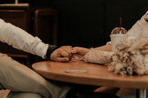 a couple sitting at a table holding hands 