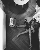 a child sitting on a floor playing a guitar 