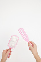 a woman holding hair brushes 