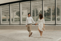 casual portrait of a bride and groom walking holding hands 