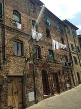 clothes on clotheslines hanging from a brick building in Italy 