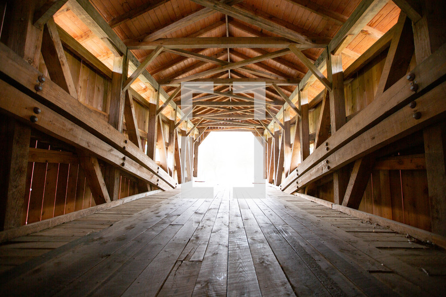 Wooden covered bridge leading to bright opening