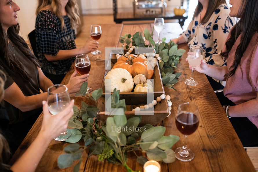 women sitting at a table with wine glasses with fall decor 