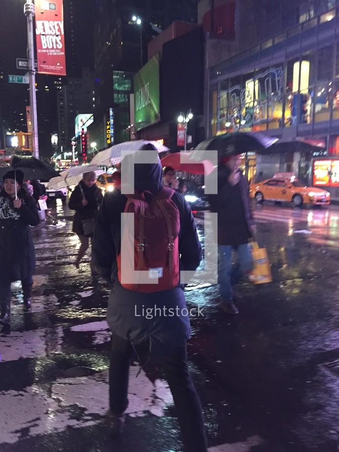 people with umbrellas walking at night in NYC 