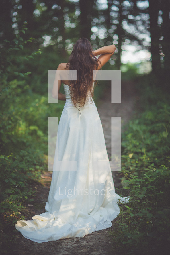 bride with her back to the camera standing in a forest 