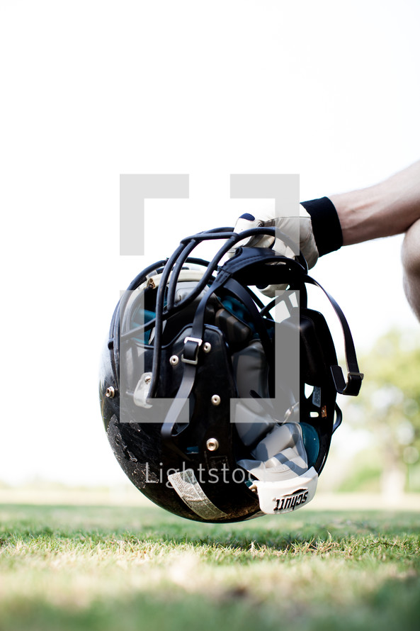 football player picking up his helmet 