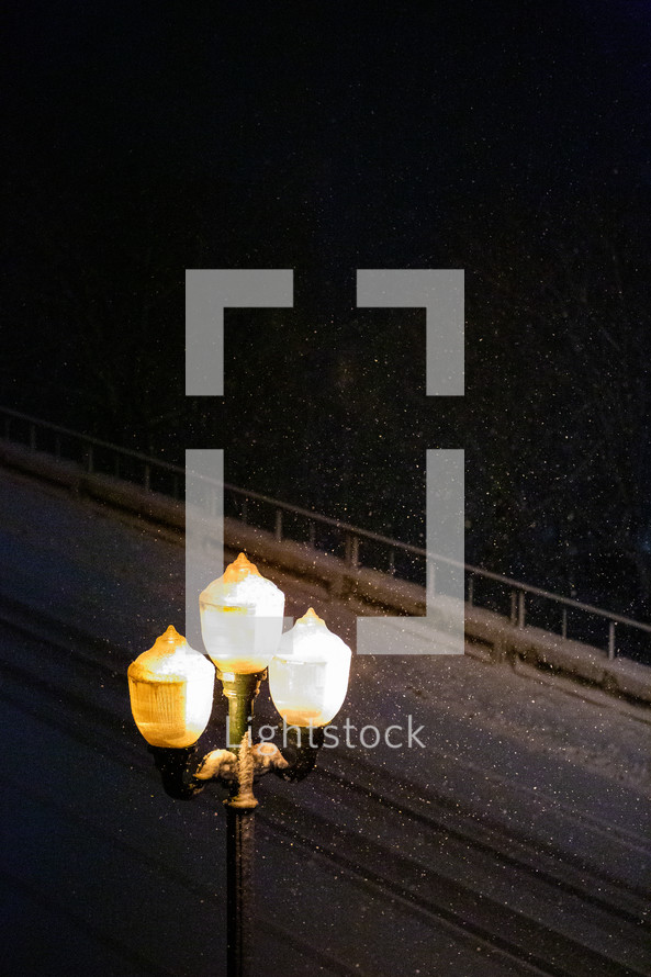 falling snow and a glowing street lamp 